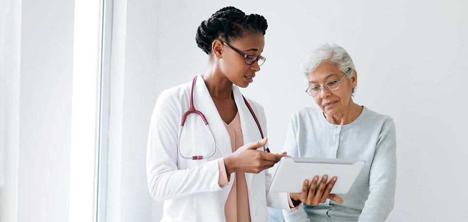 Médica conversando com uma idosa.