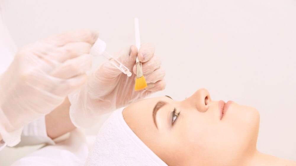Profissional realizando procedimento estético no rosto de uma mulher.